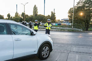 Widoczni umunudrowani policjanci i radiowozy oraz kibice w drodze na mecz