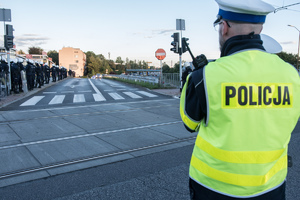 Widoczni umunudrowani policjanci i radiowozy oraz kibice w drodze na mecz