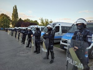 Widoczni umundurowani policjanci i radiowozy oraz kibice w drodze na mecz