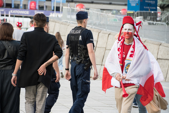 Zdjęcie kolorowe: umundurowani policjanci podczas patrolu wśród kibiców.