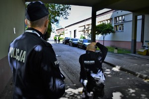 Na zdjęciu na pierwszym planie umundurowany policjant, przed nim stoi pracownik Kopalni Guido, który robi zdjęcie.