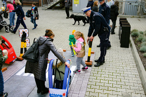 Zdjęcie. Widoczna grupa osób na placu, w tym umundurowani policjanci. Ponadto pies