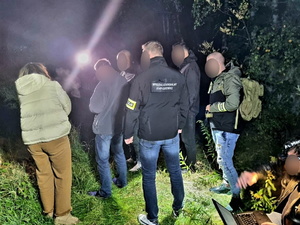 zdjęcie przedstawia policjantów wykonujących czynności z zatrzymanym w zaroślach