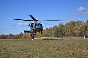 zdjęcie przedstawia policyjny śmigłowiec w trakcie lądowania