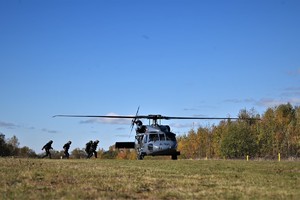 zdjęcie przedstawia policyjny śmigłowiec do którego podbiegają policjanci