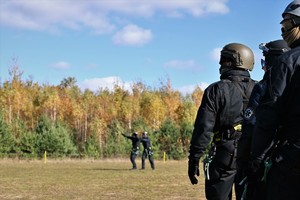 zdjęcie przedstawia policjantów oczekujących na lądowanie śmigłowca
