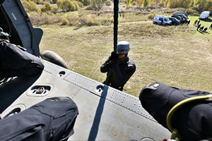 zdjęcie przedstawia policjanta desantujacego się ze śmigłowca przy użyciu liny