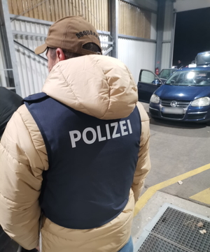 policjant w kamizelce kuloodpornej przy samochodzie