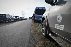 Zdjęcie. Widoczne samochody Policji i innych służb w terenie leśnym