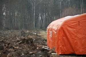 Zdjęcie. Widoczny namiot straży oraz policjanci w terenie leśnym