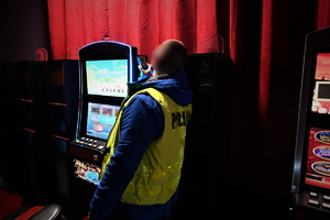 Zdjęcie przedstawia wnętrze salonu gier. Na zdjęciu widać nieumundurowanego policjanta oraz maszynę do gier.