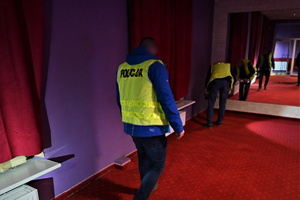 Zdjęcie przedstawia wnętrze salonu gier oraz dwóch nieumundurowanych policjantów.