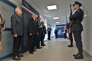 Zdjęcie. Widoczni umundurowani policjanci i uczestnicy uroczystości stojący w korytarzu