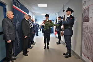 Zdjęcie. Widoczni umundurowani policjanci i uczestnicy uroczystości stojący w korytarzu