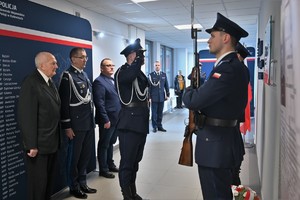 Zdjęcie. Widoczni umundurowani policjanci i uczestnicy uroczystości stojący w korytarzu