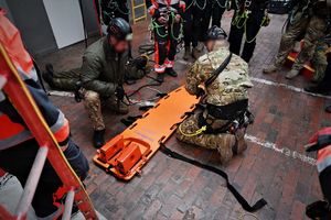 zdjęcie przedstawia dwóch policjantów pokazujących pozostałym jak przygotować nosze do transportu poszkodowanego