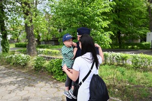 zdjęcie przedstawia policjanta w objęciach kobiety gratulującej mu przyjęcia do Policji. policjant trzyma na rękach dziecko