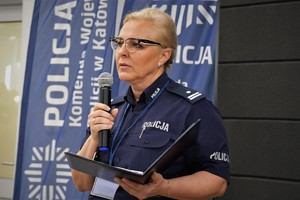 Zdjęcie. Widoczna umundurowana policjanta z mikrofonem w ręce