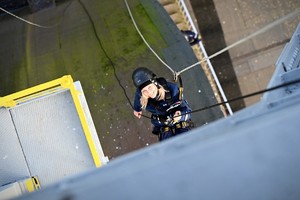 Zdjęcie. Umundurowany policjant podczas wspinaczki na linie w obrębie szybu kopalnianego