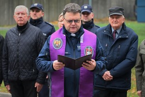 Zdjęcie. Policyjny kapelan odmawia modlitwę, w tle uczestnicy uroczystości