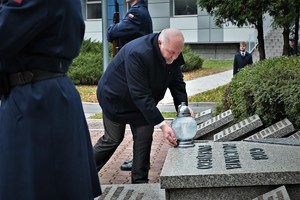 Zdjęcie. Uczestnik uroczystości kładzie znicz na Grobie Policjanta Polskiego