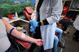 Na zdjęciu ręka mężczyzny oddającego krew, obok stoi pielęgniarka.