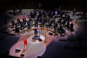 Na zdjęciu widać scenę, orkiestrę, dyrygenta i wokaliskę