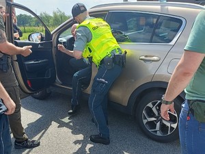 Zdjęcie funkcjonariuszy Służb Celno-Skarbowej w trakcie wyprowadzania osoby zatrzymanej z pojazdu.