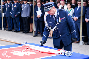 kolorowe zdjęcie przedstawiające Oficera Policji stojącego obok sztandaru