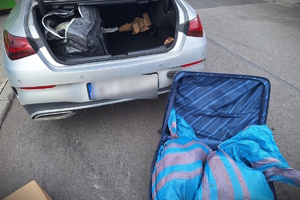 Zdjęcie samochodu z leżącą obok niego walizką