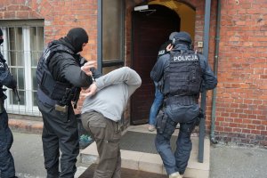 dwaj policjanci prowadzą zatrzymanego mężczyznę