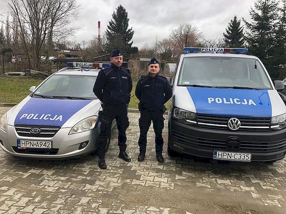 Policjanci stoją przy radiowozie