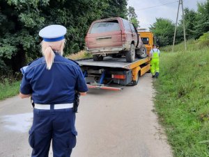 policjanci pracują na miejscu wypadku. Samochód leżący w rowie