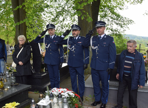 policjanci oddają honory przed grobem policjanta, który poległ na służbie