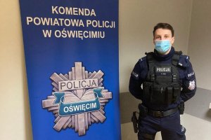 policjant pozujący przy banerze KPP oświęcim