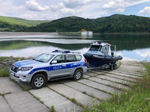 przy akwenie radiowóz z przyczepą, na której jest policyjna motorówka