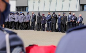 Policjanci z flagą zza pleców przed nimi policjanci zaproszeni na uroczystośc