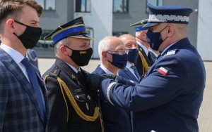 Komendant przypina medal piątemu odznaczonemu