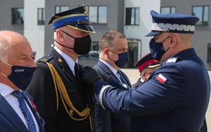 Komendant przypina medal ósmemu odznaczonemu