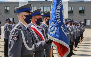 Policjanci ze sztandarem za nimi szereg mianowanych