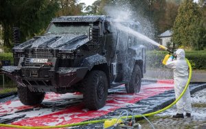 65 strażak w kombinezonie spryskuje środkiem neutralizującym pojazd policyjny