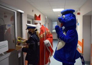 policjantka z Mikołajem i Inspektorem Wawelkiem wręczają prezenty
