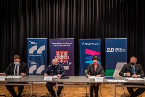 przy stole siedzą przedstawiciele: Radia Kraków, Komendy Wojewódzkiej Policji w Krakowie, Urzędu Małopolskiego i Zakładu Ubezpieczeń Społecznych