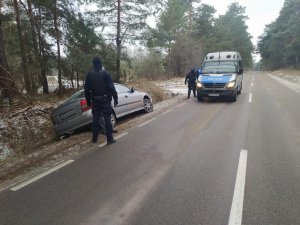 policjanci zabezpieczają miejsce kolizji, samochód osobowy w rowie