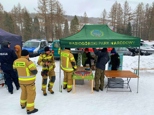 strażacy stojący przy stoisku babiogórskiego parku narodowego