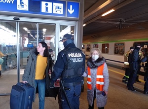 funkcjonariusz udziela informacji kobiecie na jednym z peronów dworca