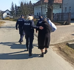 Policjanci pomagają kobiecie dostać się na teren ośrodka