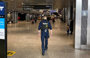 policjant patrolujący lotnisko wewnątrz budynku, widoczny tyłem do zdjęcia