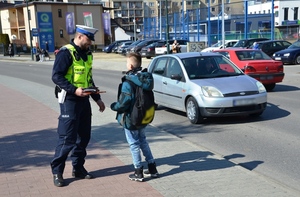 policjant wręcza chłopcu odblask