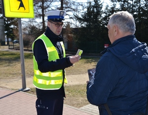 policjant wręcza mężczyźnie odblask